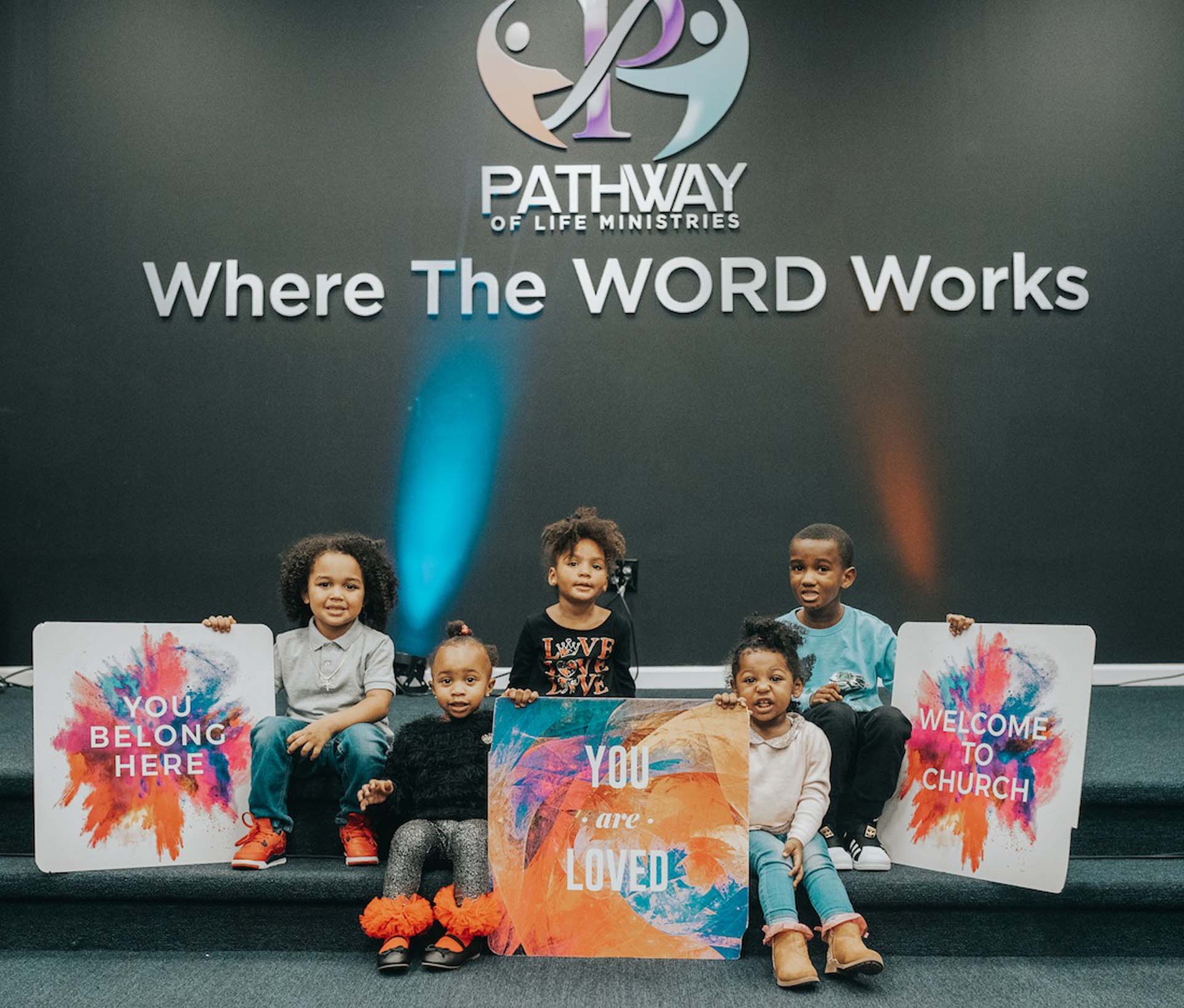 Kids Gathered Around Where The WORD Works sign